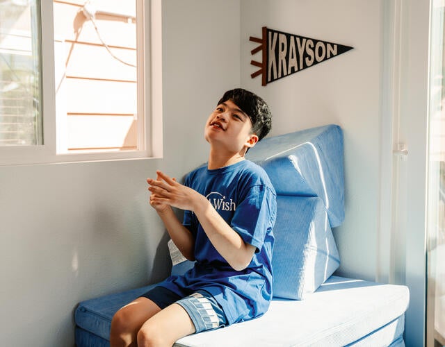 Wish kid Krayson sitting in his new therapy clubhouse