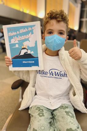 Harrison at the airport wearing his wish shirt and holding his sign