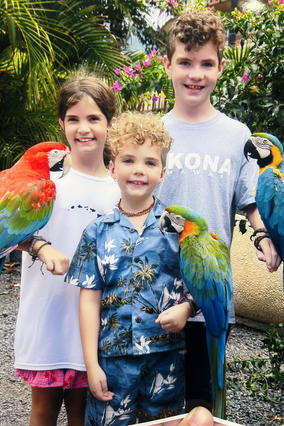 Harrison and his siblings holding bright colored tropical birds